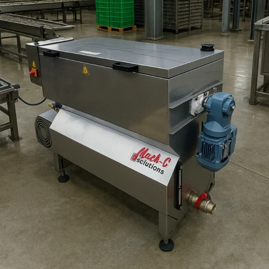 Na zdjęciu widoczna jest myjka TRAY WASHER 100 w oryginalnym wyglądzie, ustawiona w hali produkcyjnej. W tle znajdują się wytłaczanki i elementy przemysłowej linii, co podkreśla zastosowanie maszyny w myciu i dezynfekcji tacek.