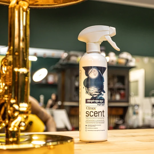 Buteleczka z patyczkami zapachowymi Clinex Scent Magiczna Noc stoi na drewnianym blacie w salonie fryzjerskim, co podkreśla, że produkt jest przeznaczony do profesjonalnych wnętrz.