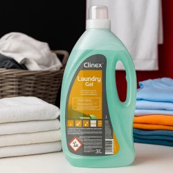 Duży pojemnik profesjonalnego żelu do prania Clinex Laundry Gel Świeży, stojący na podłodze w pralni obok suszarki i kosza na brudne pranie.