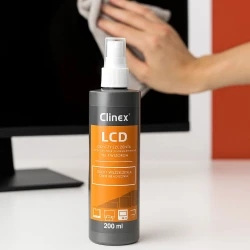 Butelka profesjonalnego płynu Clinex LCD do czyszczenia ekranów, którym ręka skutecznie czyści monitor.