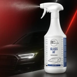 Butelka płynu FCC Glass Anti-Fog, przeznaczonego do mycia i zabezpieczania szyb w samochodzie, stoi na tle czarnego auta.