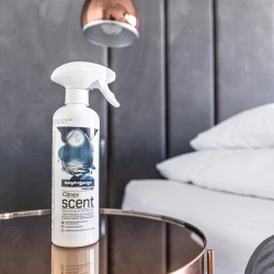 Buteleczka Clinex Scent Magiczna Noc stoi na szklanym stoliku w sypialni, co podkreśla, że produkt jest przeznaczony do wnętrz mieszkalnych.