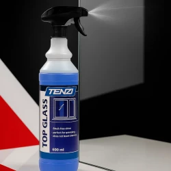 Butelka profesjonalnego płynu do mycia szyb i luster TENZI Top Glass jest używana do spryskiwania, a za nią widoczne jest czyste lustro, co ukazuje przeznaczenie produktu.